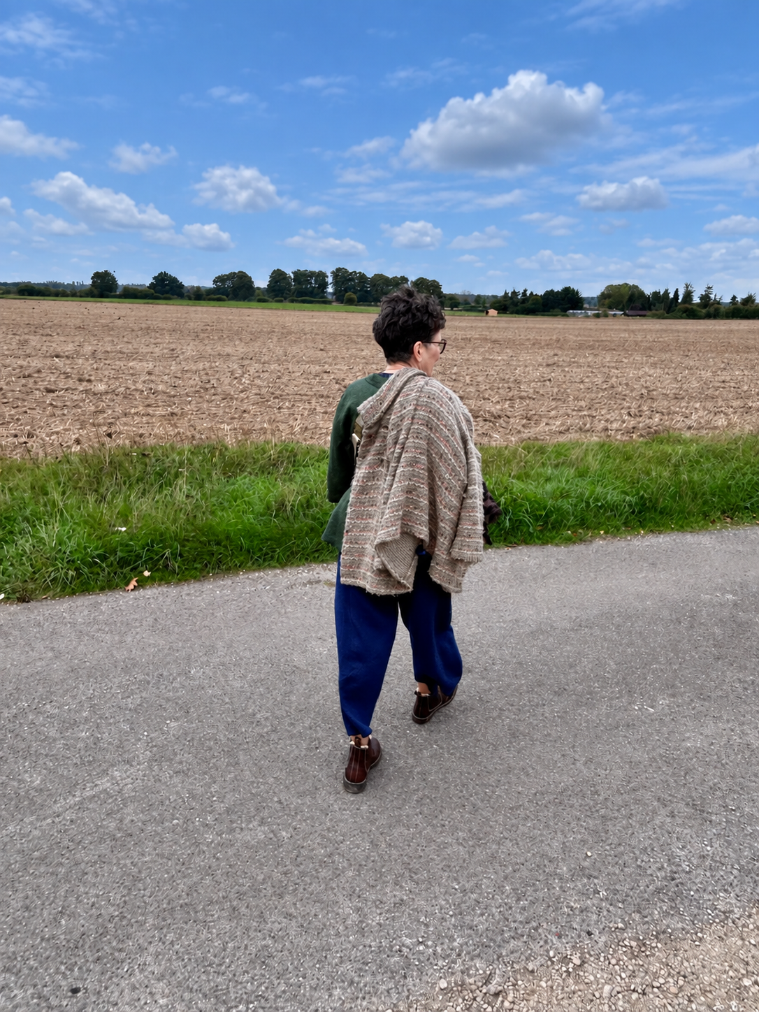 Isobel walking along a country lane in her blue linen trousers and olive green top