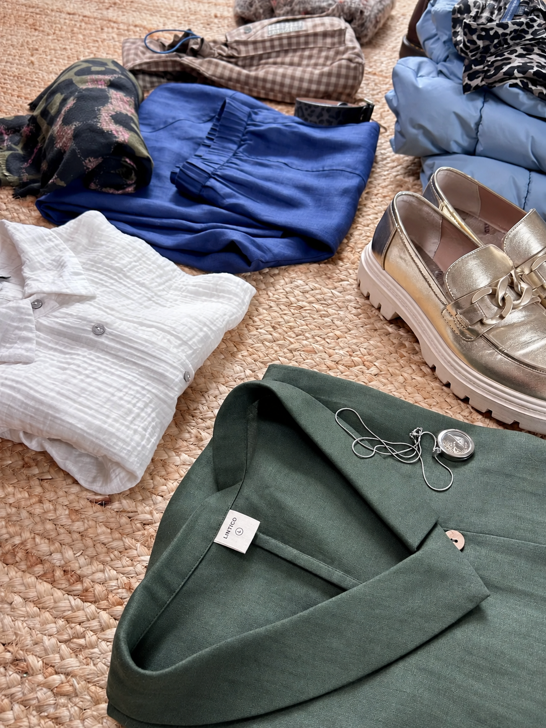 A selection of blue linen trousers, shirts and shoes laid out for the city break